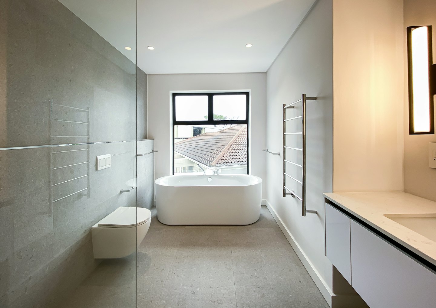 Modern bathroom with white freestanding tub and grey tile.
