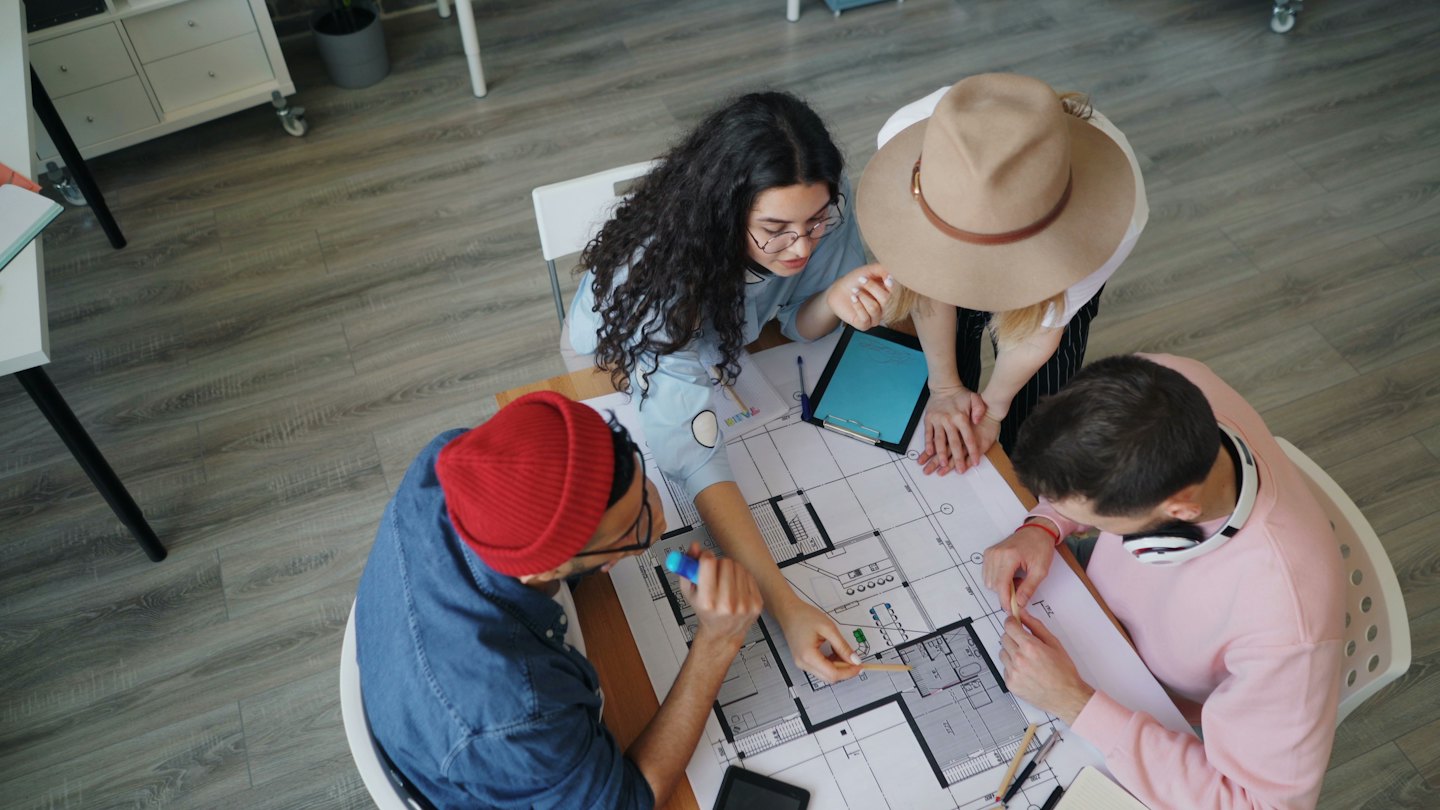 Young professionals discussing architectural blueprints at a modern table.