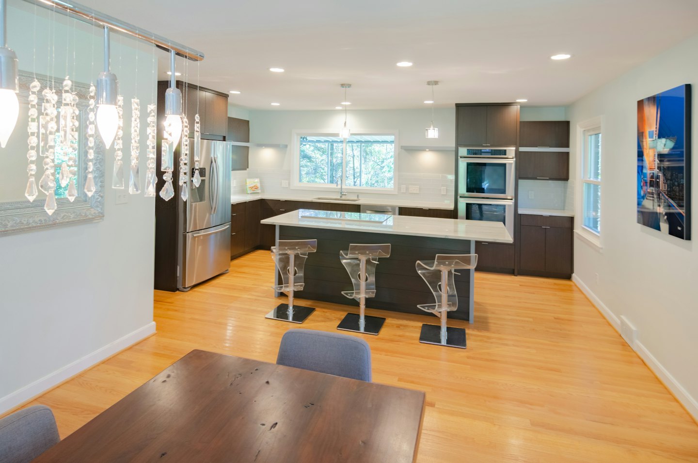 Modern kitchen and dining area with light floors and blue-green walls.