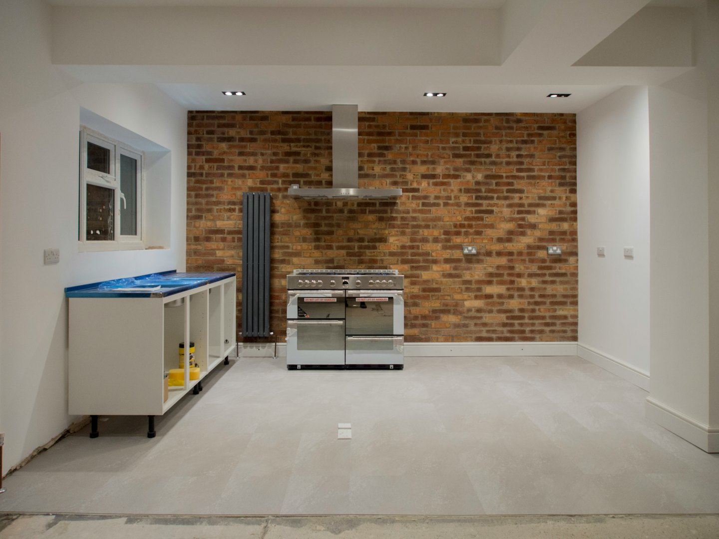 Modern kitchen under renovation with brick walls and new cabinets.