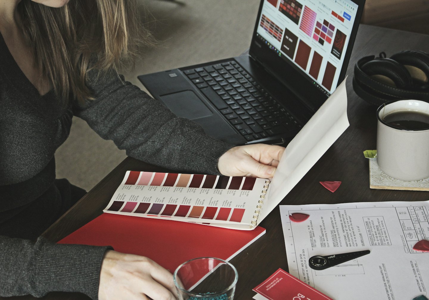 Designer reviews color swatches on a laptop and in a book.